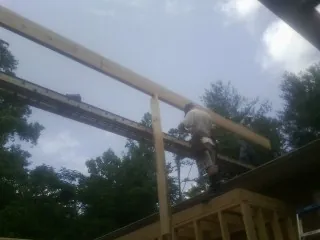 Carpenter setting a ridge beam over a new addition frame — Ice Dam Removal by Roofing Brothers in Export