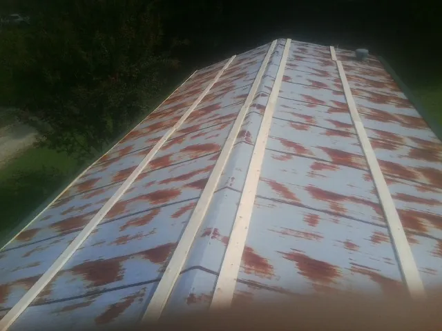 Rusted metal roof panels with new wood purlins before replacement — Storm Damage Roof Repair in Export by Roofing Brothers