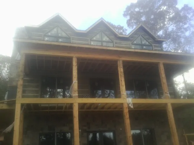 Dormers and porch framing on a large log home under construction — Roof Coating work by our crew in Export